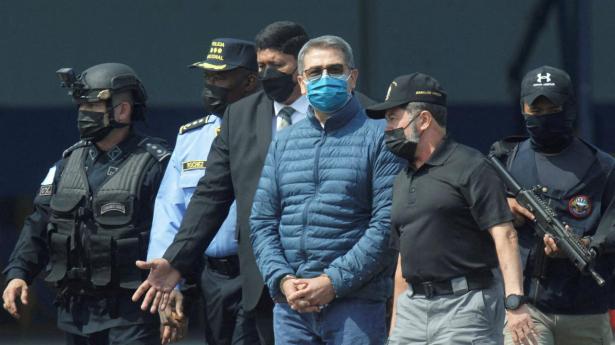 Honduras ekspræsident Juan Orlando Hernandez med det blå mundbind blev i 2022 udleveret fra Honduras til USA, hvor han sidste år blev idømt en dom på 45 års fængsel. Honduras vil have ekspræsidenten anholdt, efter at Donald Trump i november valgte at benåde ham.