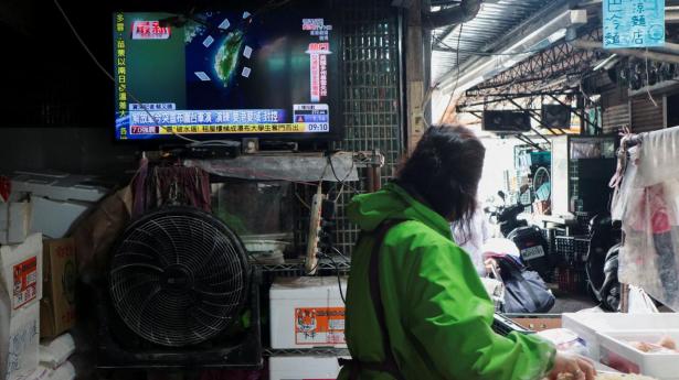 Kvinde, som arbejder i en madbod i Taipei i Taiwan, ses mandag ved et fjernsyn, der viser nyheden om Kinas "Just Mission 2025"-militærøvelser omkring Taiwan.