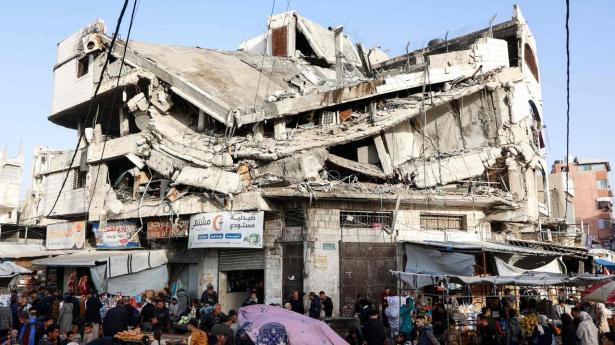 Palæstinensere står onsdag uden for en butik i Gaza By, der flere steder er blevet ødelagt af israelske angreb under krigen.