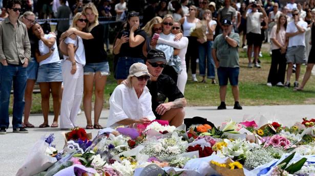Folk sørger ved Bondi Beach i Sydney, dagen efter at 16 mennesker blev dræbt i et masseskyderi - inklusive en af de to gerningsmænd.