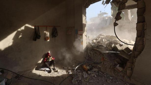 TOPSHOT - AFP PICTURES OF THE YEAR 2025 A Palestinian boy holds a book as he sits in rubble of a house, following overnight Israeli strikes, at the Nuseirat refugee camp in the central Gaza Strip on April 29, 2025.. Israel resumed its military campaign in the Gaza Strip on March 18. A ceasefire agreement that had largely halted the fighting for two months before that collapsed over disagreements between Israel and the Palestinian militant group Hamas, whose 2023 attack triggered the war. (Photo by Eyad BABA / AFP) / AFP PICTURES OF THE YEAR 2025