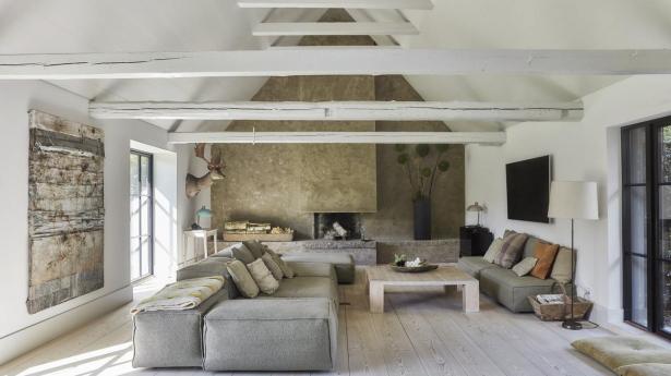 I den nye stue har de skabt en hyggekrog med en hel pejsevæg og en stor sofa fra Anker & Co. og en specialbygget pejs. Det store maleri er af Per Beier fra Samsø. Sofabordet er designet af Peter Simonsen og har fulgt familien gennem tre huse. Pejsen er bygget op og derefter spartlet med indfarvet mikrocement og foret indvendig med søsten og granit.