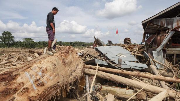 En mand står oven på ruinerne af sit hus i en landsby i Aceh Tamiang i det nordlige Sumatra den 11. december.
