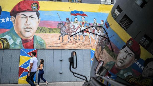 Det statslige olieselskab Petroleos de Venezuela (PDVSA) har onsdag fastholdt, at landets eksport af råolie er upåvirket af melding fra Trump om blokade af sanktionerede olietankere. Billedet er fra Venezuelas hovedstad, Caracas, onsdag, hvor indbyggere kan ses passere vægmaleri af den tidligere præsident Hugo Chávez.