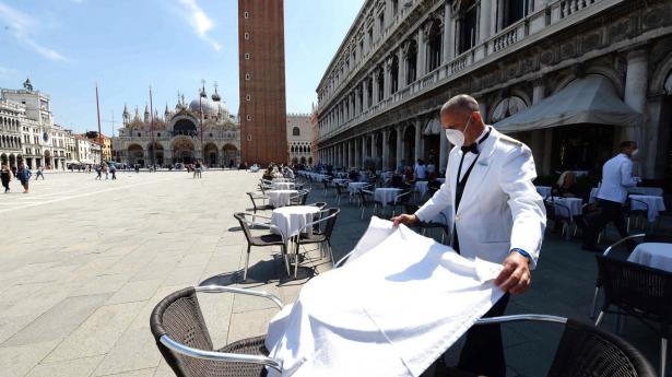 Italien er ét af de lande, der kan stå foran en aktiemæssig genrejsning, hvis verden atter bliver mere normal i 2021. Her er det en tjener, der dækker bord på den affolkede Markuspladsen i Venedig.
Arkivfoto: Andrea Pattaro/AFP/Ritzau/Scanpix