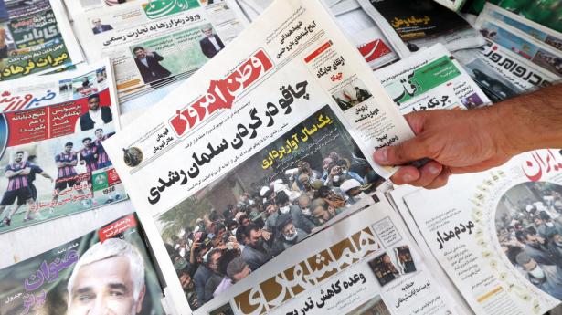 En mand viser lørdagens forside på et iransk medie, hvor der på farsi står: “Kniv i nakken på Salman Rushdie”. Foto: Atta Kenare/AFP/Ritzau Scanpix