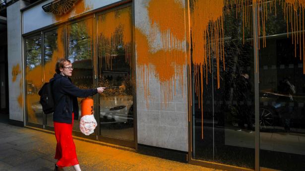 Et medlem af gruppen Just Stop Oil sprøjter orange maling ud over Aston Martins udstillingslokaler i London. Foto Isabel Infantes Ritzau/Scanpix.