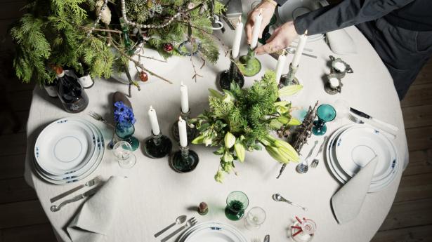 Gemina-service af Gertrud Vasegaard fra Royal Copenhagen, du fra Merci, Paris, stofservietter fra Ketty på Ærø, sølvbestik er både Sigvard Bernadotte og Arje Griegst fra Georg Jensen. Antikke Anglais-glas og klare glas med egeløvmotiv. Juledekorationen står i en krikke af Christian Poulsen. Lysetager i Leif Sigersens design. Til venstre står blå riddersporer i en antik børnetræsko. Dertil antikke tyske saltkar i sølv og MK16-stole af Mogens Koch.