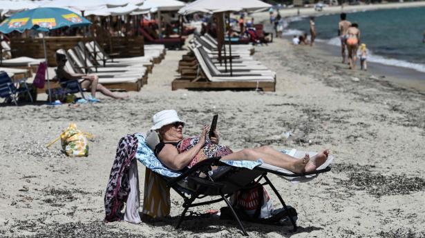 En kvinde kigger på sin telefon på stranden ved Khalkidiki i Grækenland i juni. 20.000 TDC-kunder kan ikke bruge 4G-netværket på grund af problemer med roaming. Arkivfoto: Sakis Mitrolidis/Ritzau Scanpix