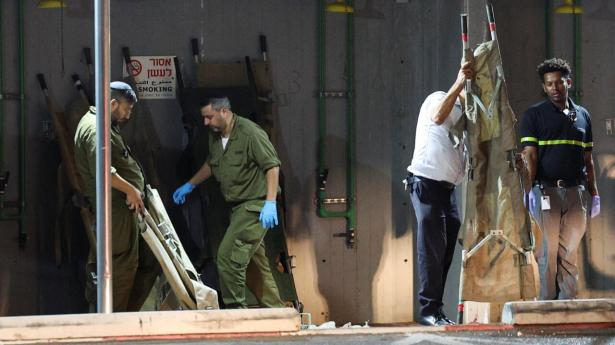 Israelske soldater og ambulancefolk henter bårer til sårede fra droneangrebet på det nordlige Israel søndag aften.