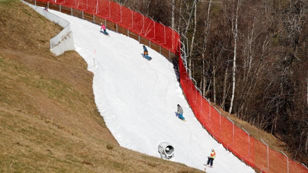 Skiers pass on a small layer of artificial snow near Gaschurn
