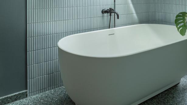 Det nye badeværelse på 5. sal, hvor pladsen under det skrå loft er udnyttet til et stort Luv-badekar af Cecilie Manz for Duravit. En grønlig terrazzoflise vækker minder hos Trude Mardal om at kigge ned i et vandfald i Norge, hendes barndomsland. Vægfliserne er mosaikfliser, såkaldte “finger tiles”, som er brugt til at gøre alle hjørner i lejlighedens badeværelser runde.