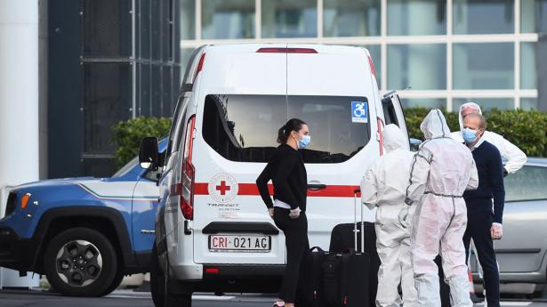 Passagerer fra krydstogtskibet Costa Luminosa, som var ramt af coronasmitte, ledsages fra skibet til en ambulance af sundhedspersonale i beskyttelsesdragter. Skibet har lagt til i havnen i byen Savona tæt ved Genova i det nordlige Italien.