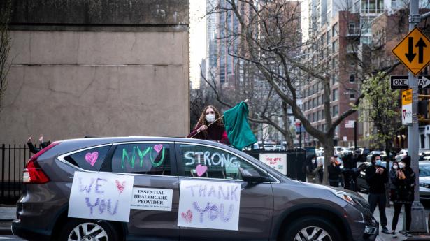 En kvinde holder et flag op for at takke sundhedspersonale udenfor NYU Langone Hospital på Manhattan i New York.
