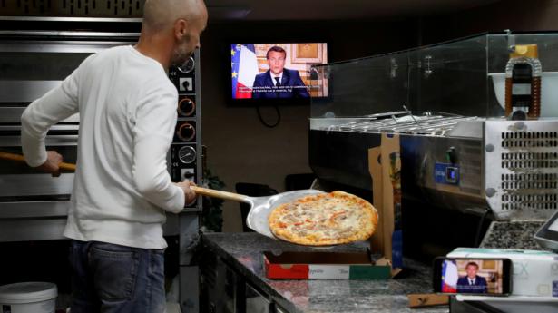 En ansat i et pizzeria i den sydfranske by Nice følger med i præsident Emmanuel Macrons tale til nationen mandag aften.
