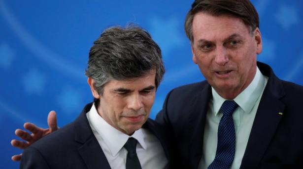 Brasiliens præsident, Jair Bolsonaro (t.h.), lægger armen på afgående sundhedsminister Nelson Teichs skulder, da denne blev taget i ed den 17. april. Nu har Teich indgivet sin afsked.