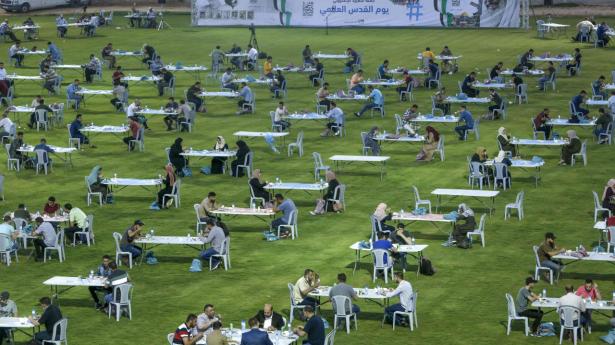 Med behørig afstand mellem sig indtog palæstinensere i Gaza fredag aften iftar-måltidet, der afslutter den daglige faste under ramadanen. Hamas-bevægelsen, der kontrollerer Gaza, havde opstillet hundredvis af borde på et fodboldstadion i Gaza City.