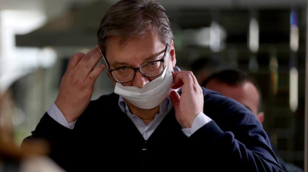 Serbiens præsident, Aleksandar Vucic, tager en ansigtsmaske på ved et valgsted i Beograd søndag. Den første prognose spår en solid sejr til ham og hans parti, men meget tyder på en lav valgdeltagelse.