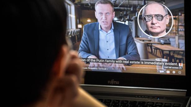 En kvinde ser den YouTube-video, som oppositionsleder Aleksej Navalnyj (på skærmen) har uploadet. Den beskylder Putin for at have brugt milliarder på at bygge et luksuspalads ved Sortehavet. Det er blevet Navalnyjs mest sete video med over 100 millioner visninger.