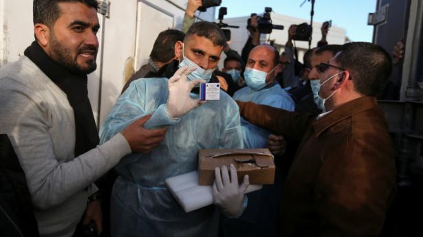 Palæstinensiske sundhedsmedarbejdere viser søndag en kasse med den russiske coronavaccine Sputnik V frem ved grænseovergangen Rafah i det sydlige Gaza, hvor vaccinerne ankom fra De Forenede Arabiske Emirater søndag.