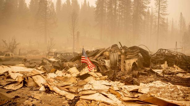 Et amerikansk flag er placeret på en udbrændt brandbil i byen Greenville, som er forvandlet til aske. Skovbranden Dixie har bredt sig og truer omkring 14.000 huse og bygninger. Det er den næststørste skovbrand i Californien nogensinde.