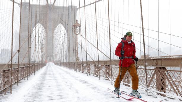 En person krydser Brooklyn Bridge i New York på ski lørdag. Den amerikanske østkyst er ramt af snestorm mange steder.