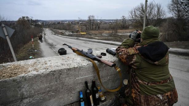 En ukrainsk soldat spejder ud over området med en kikkert ved et checkpoint ved den vej nær byen Stoyanka, der fører videre til Ukraines hovedstad, Kyiv, søndag.