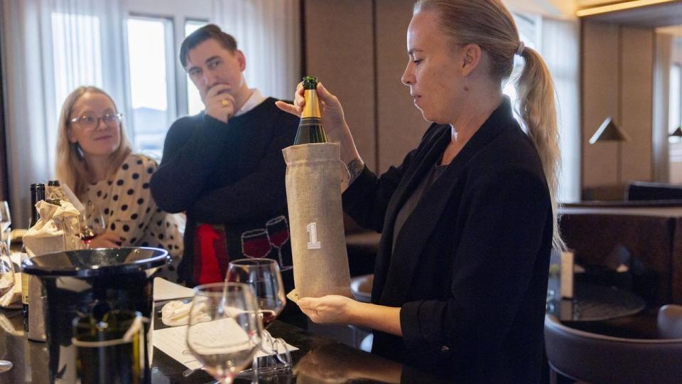 Champagnesmagningens vinder kom tilfældigvis også som smagningens første. Her afsløres den af sommelier Gin Isabel, mens kollegaerne Emmelie Danbirk og Henrik Levinsen ser til i spænding.