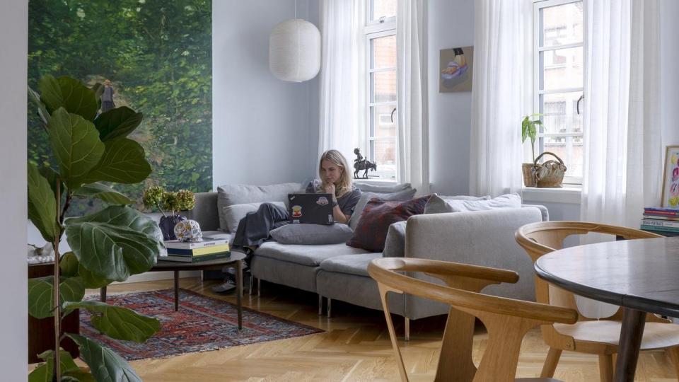 Dagligstuen, der ligger en suite med spisestuen, er indrettet med en sofa fra Ikea og et sofabord designet af Signe Weigelt for FDB. Det store overvejende grønne maleri er af Michael Kvium.