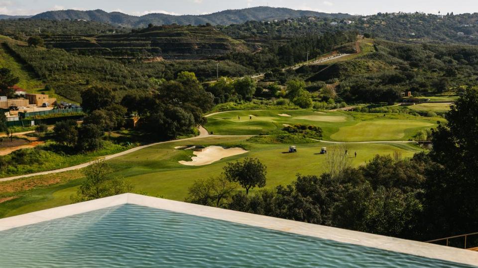 Fra poolkanten er der frit udsyn over Ombrias golfbaner, hvor spillere bevæger sig mellem greens og sandbunkere. Banen ligger i Algarves Barrocal – det kuperede overgangsområde mellem kysten og bjergene, hvor naturen har været styrende for banens udformning.