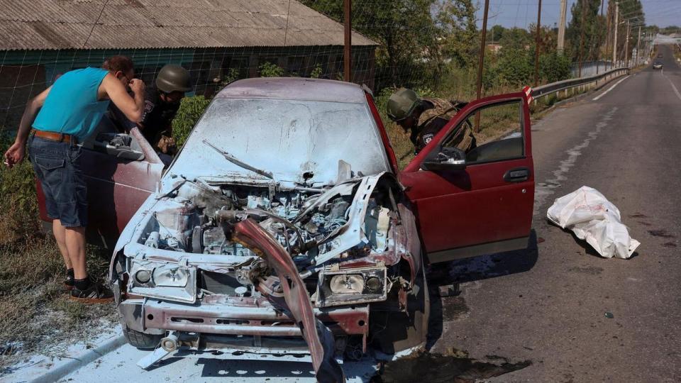Betjente undersøger en beskadiget bil, der lørdag blev angrebet med en russisk drone i Kramatorsk, der ligger nær frontlinjen.
