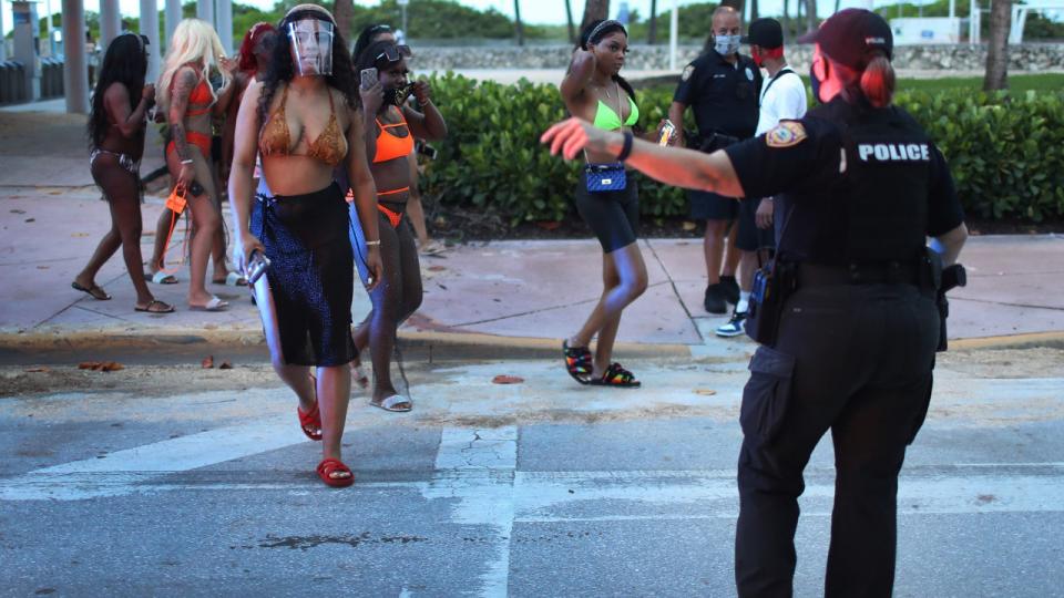 En politibetjent ved Miami Beach dirigerer folk væk fra strandområdet, hvor der i sidste uge blev indført udgangsforbud om aftenen og natten for at bremse coronasmitten. Antallet af smittede i Florida stiger markant.